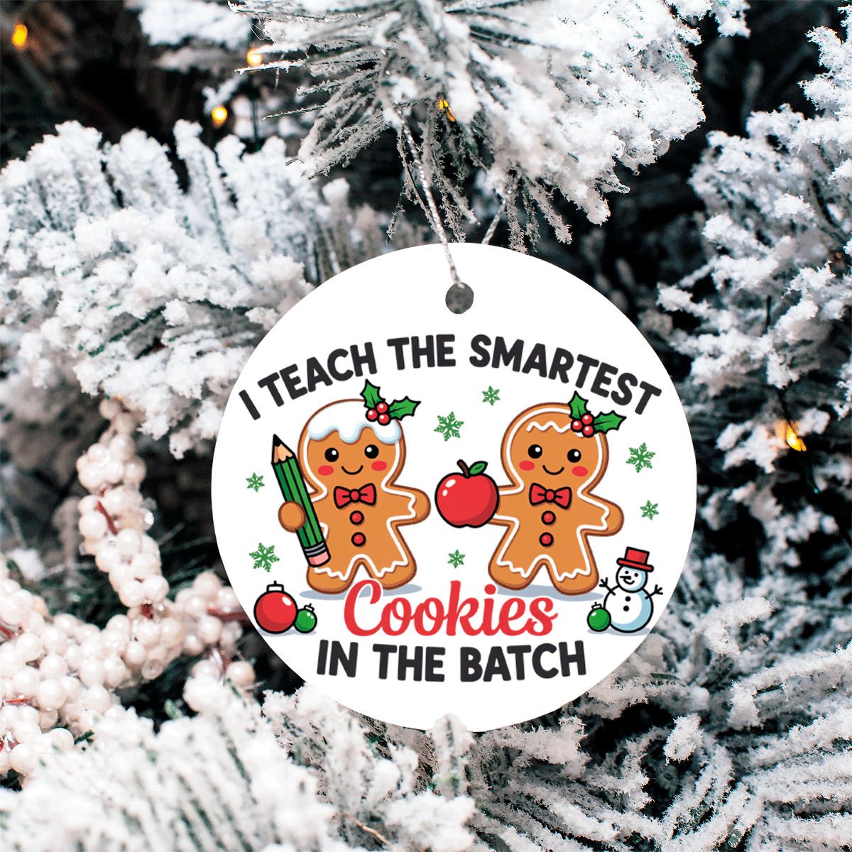 Christmas ornament with gingerbread men and text 'I teach the smartest cookies in the batch' on a snowy tree background.