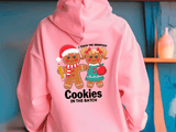 Pink hoodie with cartoon characters and text on a blue wall background