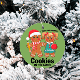 Circular green ornament with gingerbread characters on a snowy tree background