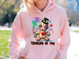Person wearing a pink hoodie with a cartoon character and 'Thinking of You' text.