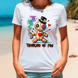 Person wearing a white t-shirt with a colorful graphic design on a beach.