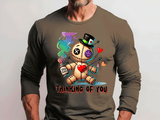 Person wearing a long-sleeve shirt with a graphic design of a voodoo doll holding a bottle of poison and text 'Thinking of You'.