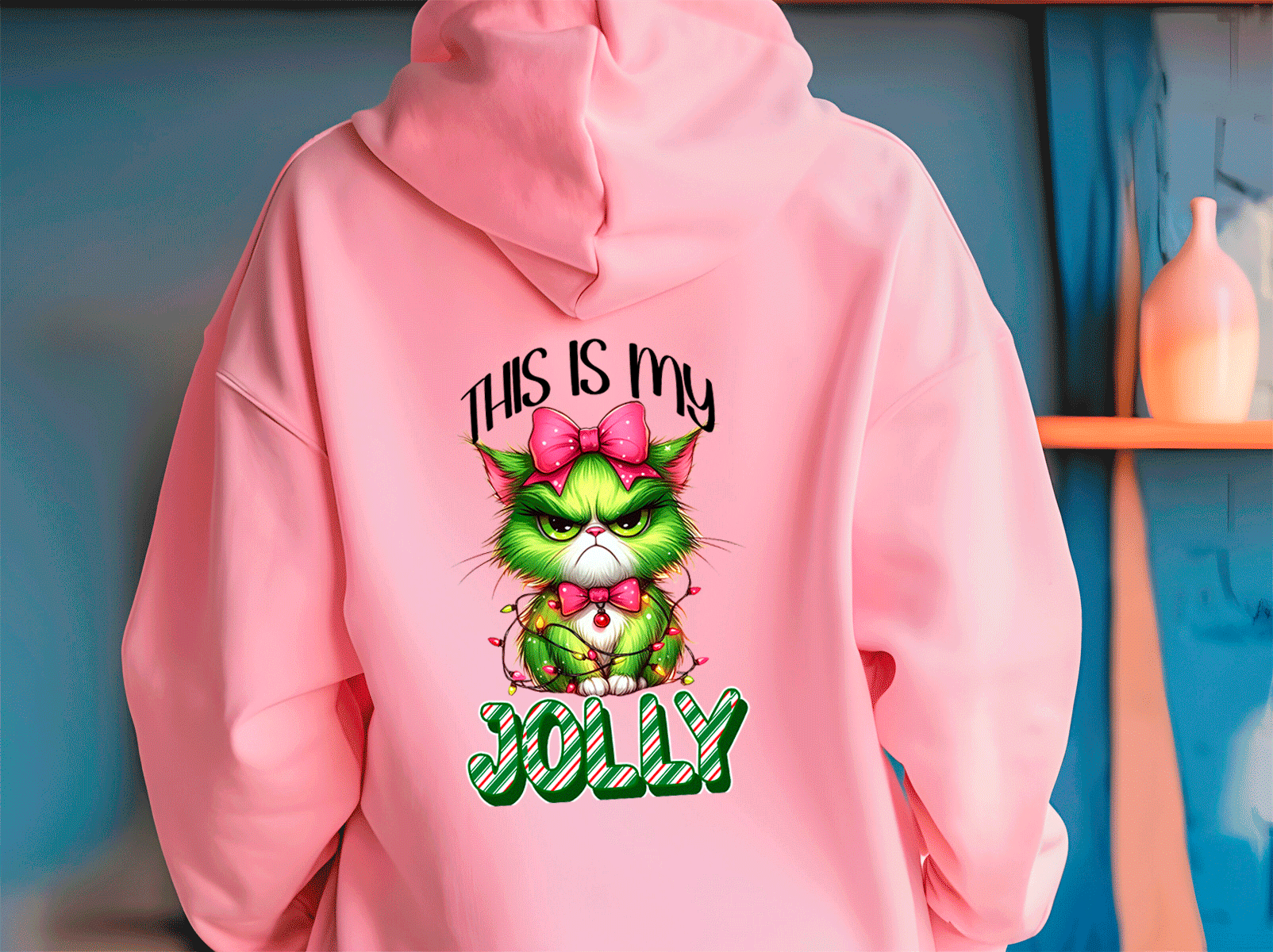 Pink hoodie with a green cat graphic and text 'This is my JOLLY' on a blue wall background.