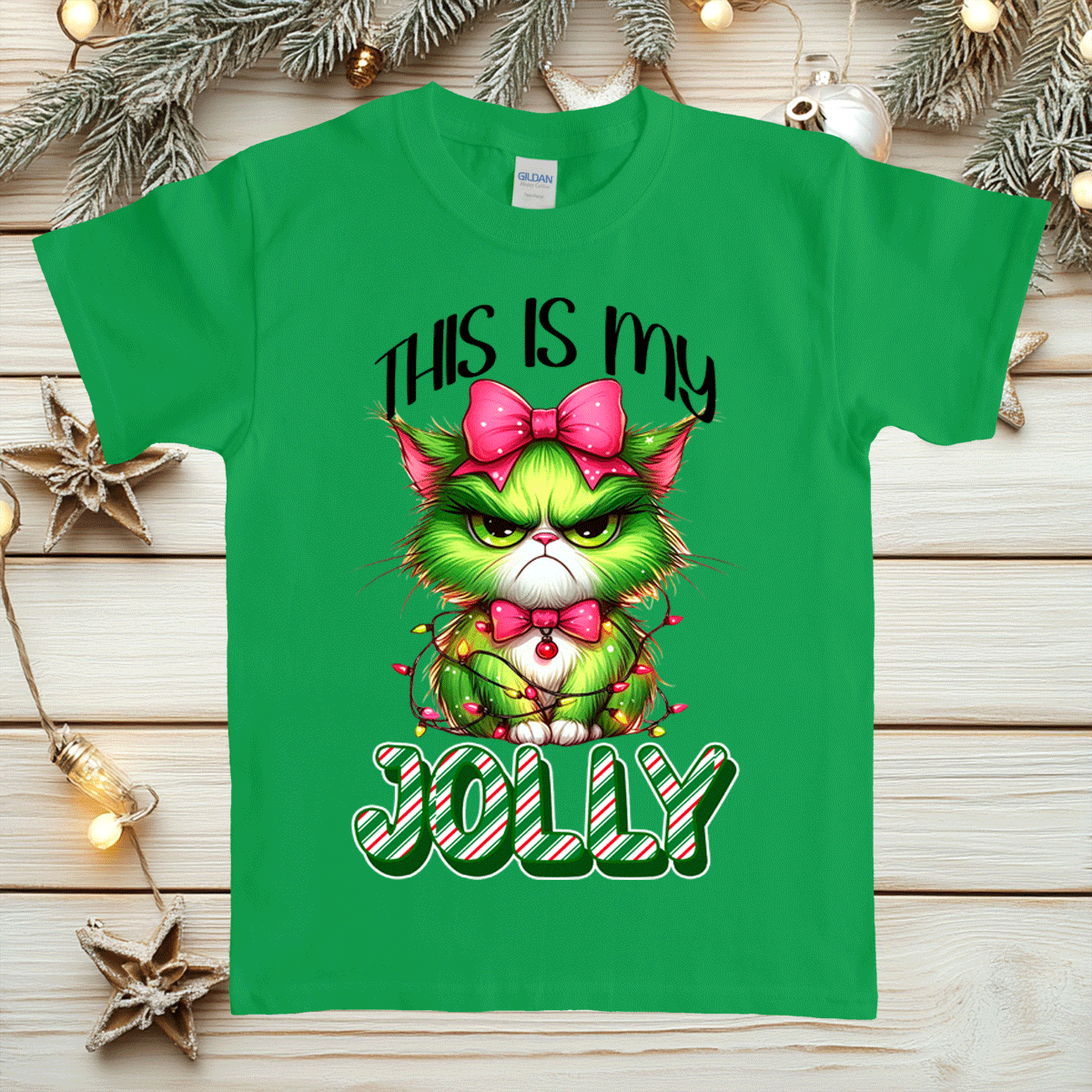 Green t-shirt with a festive design featuring a green cat with a pink bow and candy cane text on a wooden background.