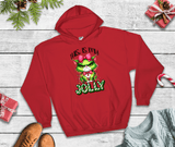 Red hoodie with Grinch design and 'This is my jolly' text on a wooden surface with Christmas decorations.