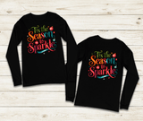 Black long-sleeve shirts with colorful text design on a wooden surface