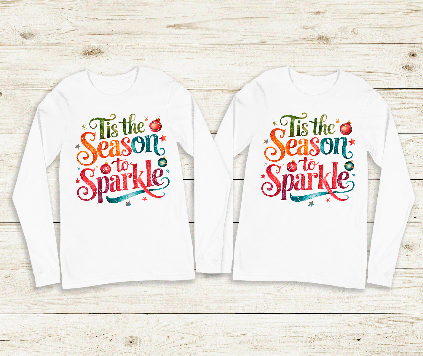 Two white long-sleeve shirts with colorful text design on a wooden surface