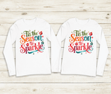 Two white long-sleeve shirts with colorful text design on a wooden surface
