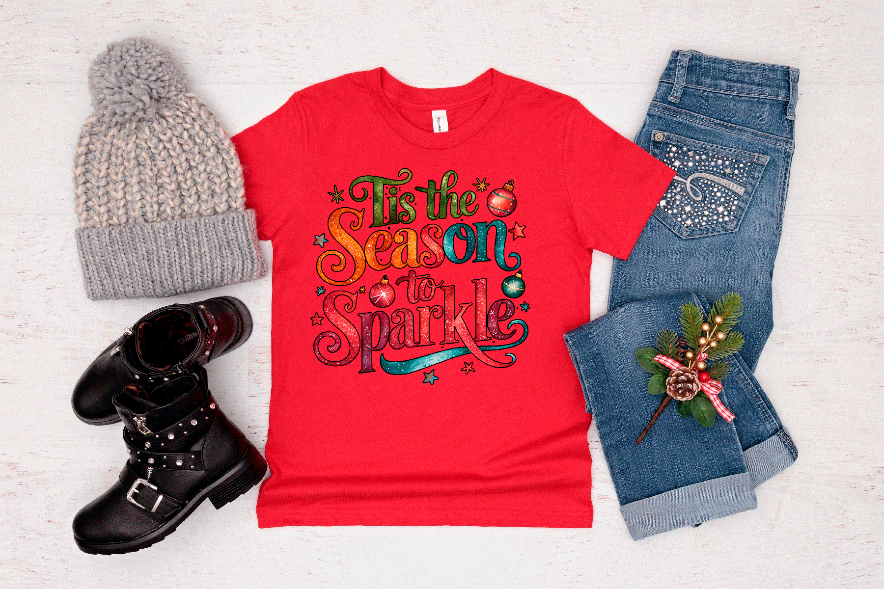 Red t-shirt with festive design, gray beanie, black boots, and jeans on a light background