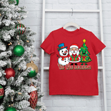 Red t-shirt with Santa Claus and snowman design next to a decorated Christmas tree.