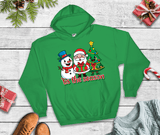 Green hoodie with Christmas design featuring Santa Claus and a snowman on a wooden surface.
