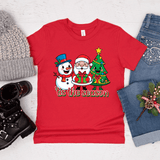 Red t-shirt with Christmas design featuring Santa, snowman, and tree, surrounded by winter accessories on a light background.