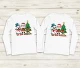 Two white long-sleeve shirts with Christmas-themed design on a wooden surface