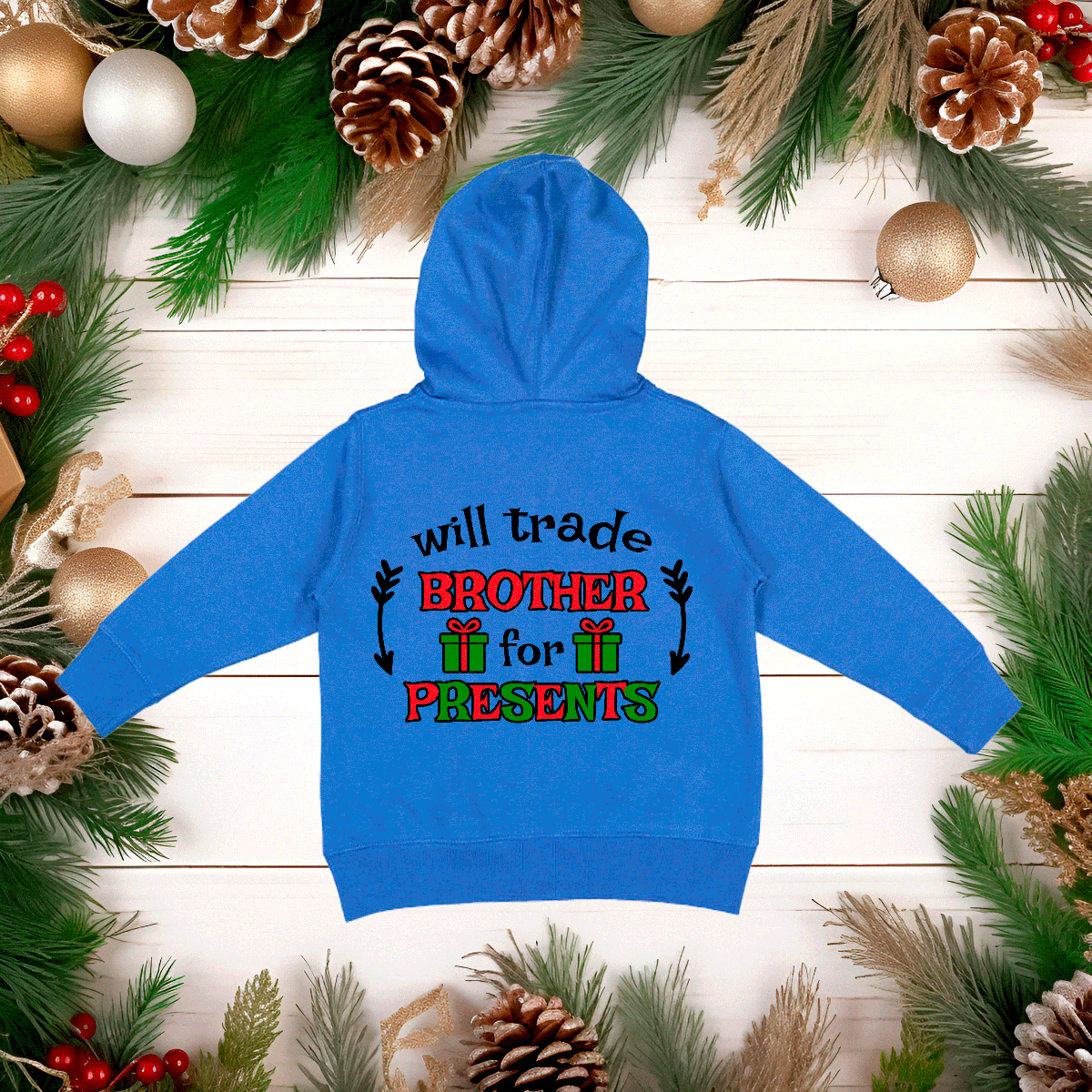 Blue hoodie with Christmas-themed text on a wooden surface with festive decorations