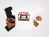 White tee with Christmas-themed text and graphics, paired with jeans and boots on a light background.