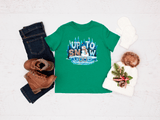 Green t-shirt with snowman graphic, jeans, boots, and a hat on a light gray background