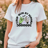 Person wearing a white t-shirt with a graphic design and text, standing in a natural setting.