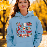 Person wearing a light blue hoodie with 'Warm & Cozy Christmas' text and decorations, standing in an autumn setting.