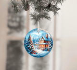 Christmas ornament with a snowy village scene hanging on a tree branch.