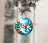Circular Christmas ornament with a snowman and festive trees hanging on a tree branch.
