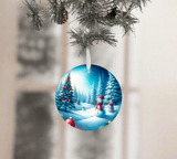 Christmas ornament with a snowy scene featuring trees and a snowman, hanging from a tree.
