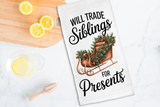Tea towel with Christmas design and text on a kitchen counter with lemons and a wooden spoon.