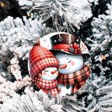 Decorative Christmas ornament with a snowman and snowperson couple on a tree.