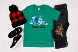 Green t-shirt with 'Winter Vibes' design, black jeans, red and black checkered beanie, and black shoes on a light gray background.