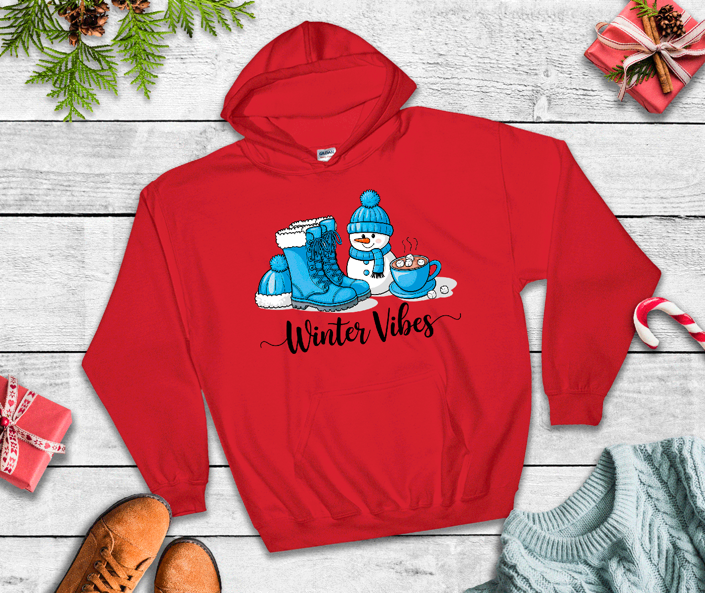 Red hoodie with 'Winter Vibes' design featuring boots and a snowman on a wooden surface.