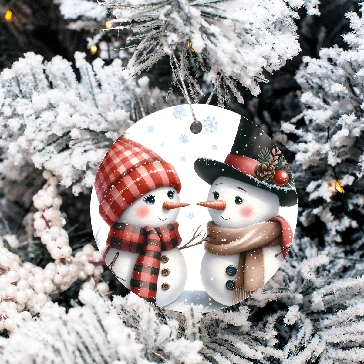 Decorative ornament with two snowmen wearing hats and scarves, hanging on a Christmas tree.