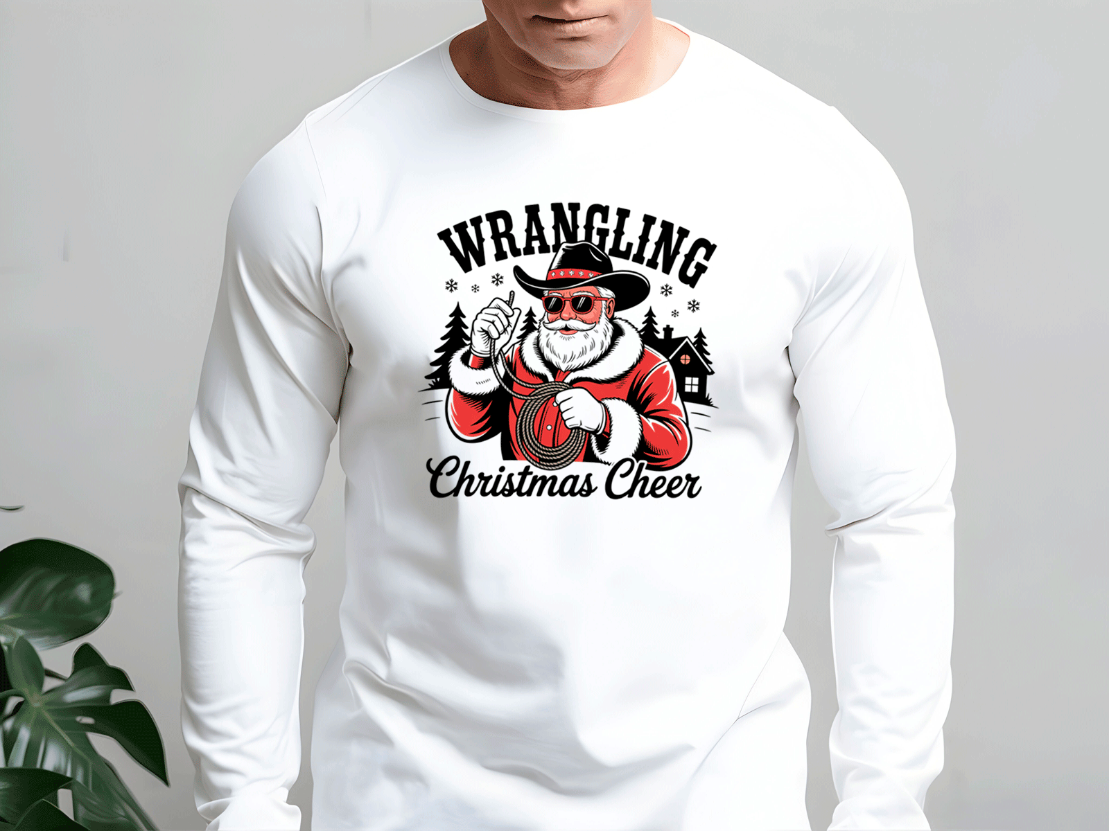 White long-sleeve shirt with a graphic design featuring a person in a Santa Claus outfit and text 'Wrangling Christmas Cheer' on a plain background.