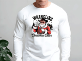 White long-sleeve shirt with a graphic design featuring a person in a Santa Claus outfit and text 'Wrangling Christmas Cheer' on a plain background.