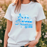 Person wearing a white t-shirt with blue text and graphics in a natural setting